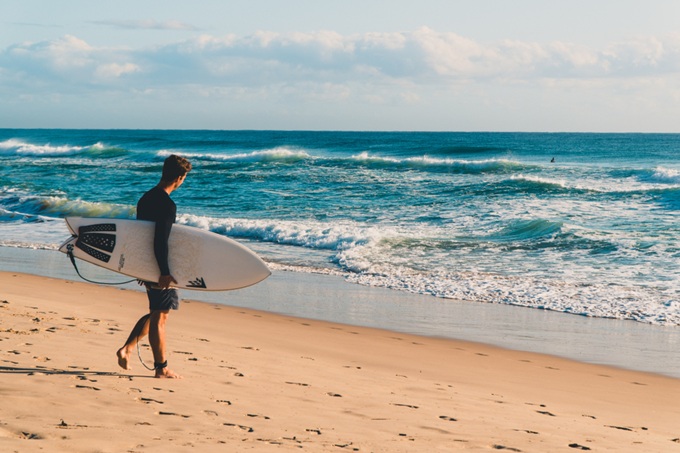 Surfař s prknem na písečné pláži v Austrálii