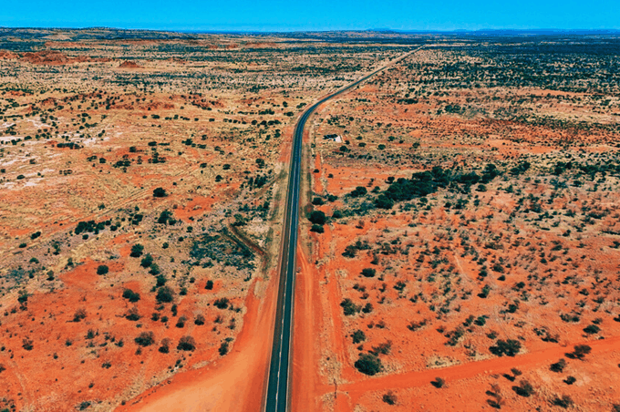 Dlouhá silnice v australském outbacku uprostřed pouštní krajiny